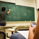 man in black and white polo shirt beside writing board