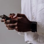 person in white dress shirt holding black smartphone